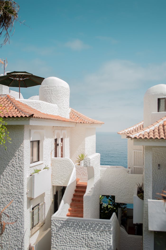services-img Elegant white Mediterranean-style houses with sea view and blue skies, perfect for coastal living.